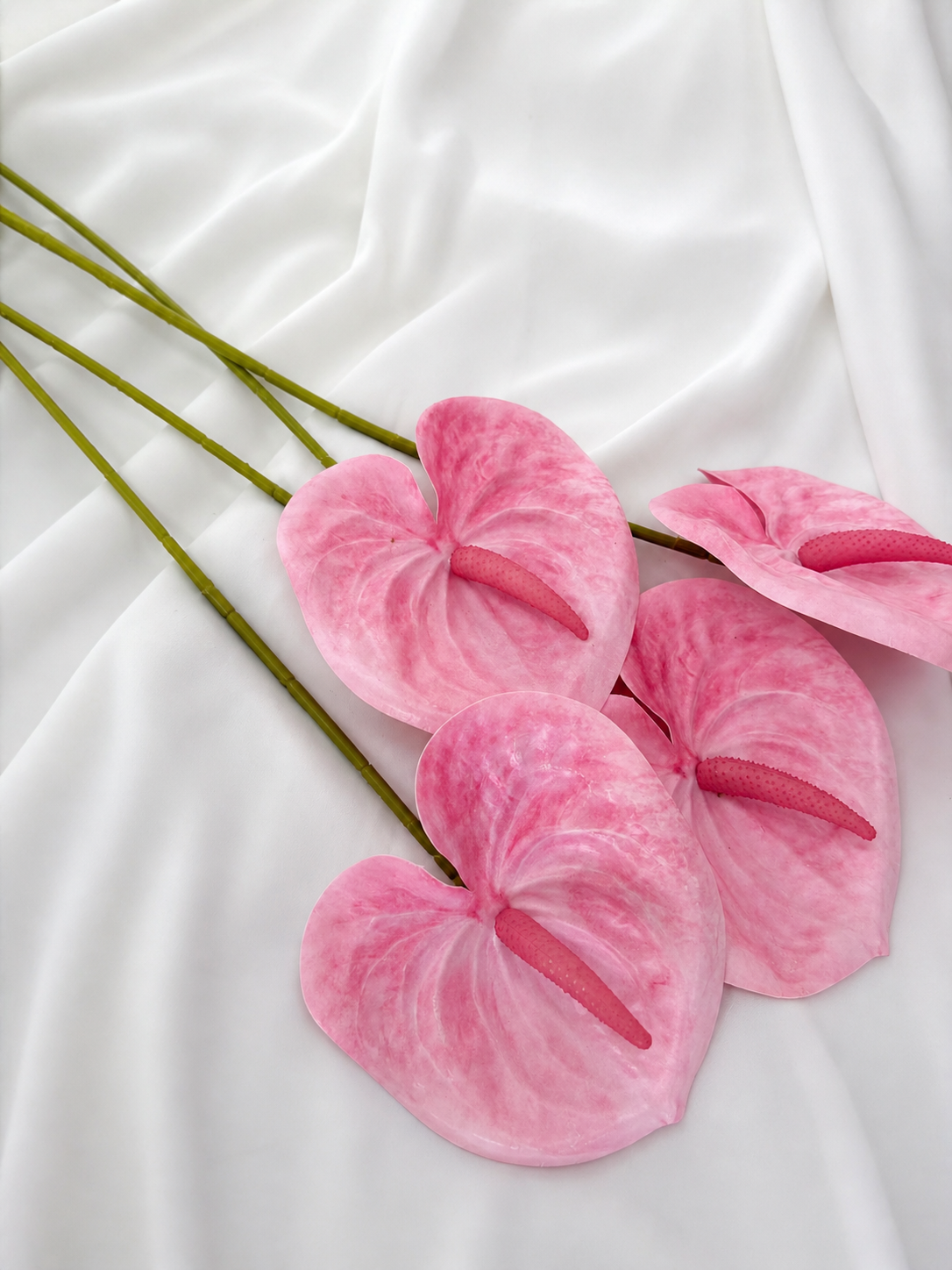 Pink artificial flowers held against a white background